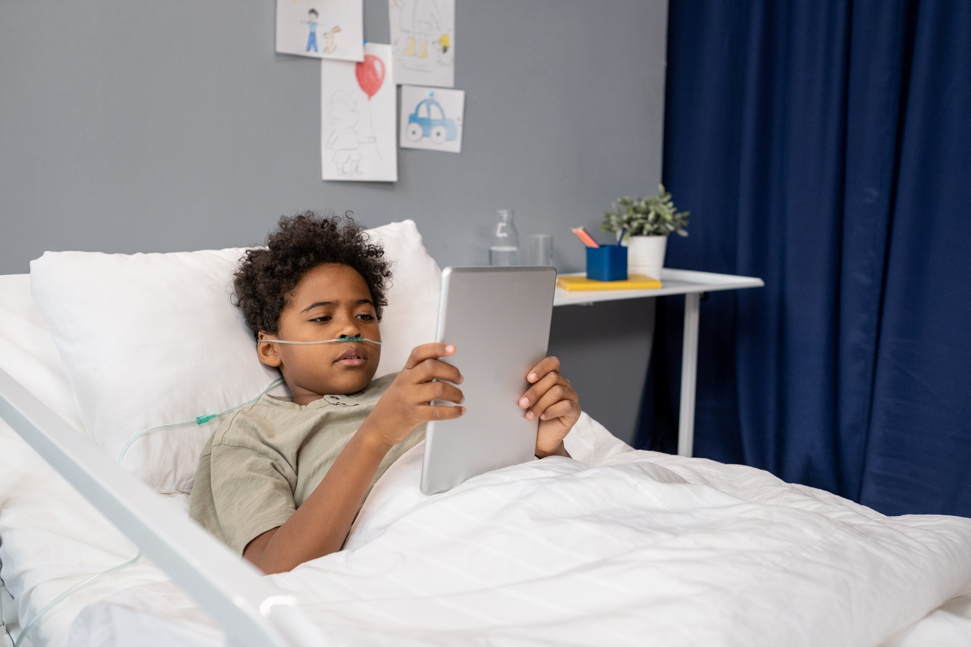 Little boy using tablet pc at hospital ward